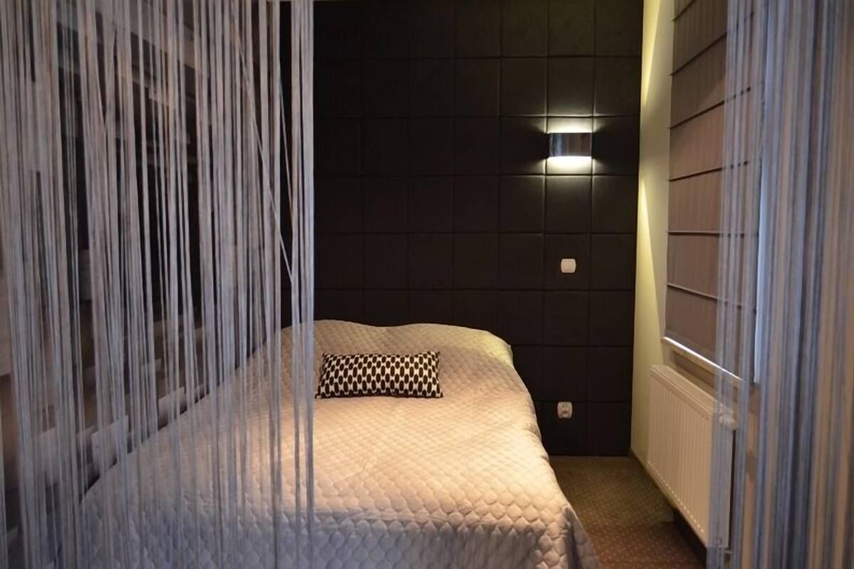 Een slaapkamer met een bed, nachtkastje, wandlamp en radiator.