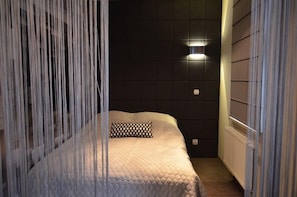 Een slaapkamer met een bed, nachtkastje, wandlamp en radiator.