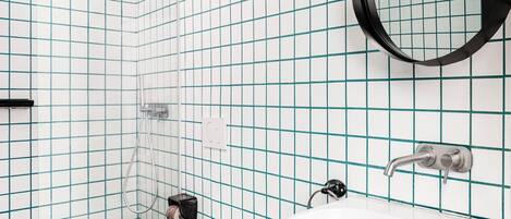A bathroom with white tiles, a white sink, a toilet, a towel rack, and a shower.