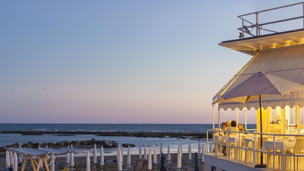 A beachside restaurant with outdoor seating and a view of the ocean. - Hotel Riviera (Anzio)