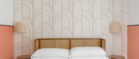 A neatly made bed with a headboard, two bedside tables, and wall-mounted lamps.