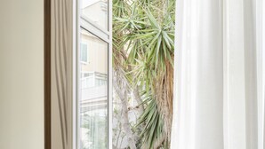 A bedroom with a large window, a bed, and a view of a tree outside. - Hotel Riviera (Anzio)