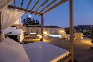 A rooftop terrace with a pool, lounge chairs, and a pergola.