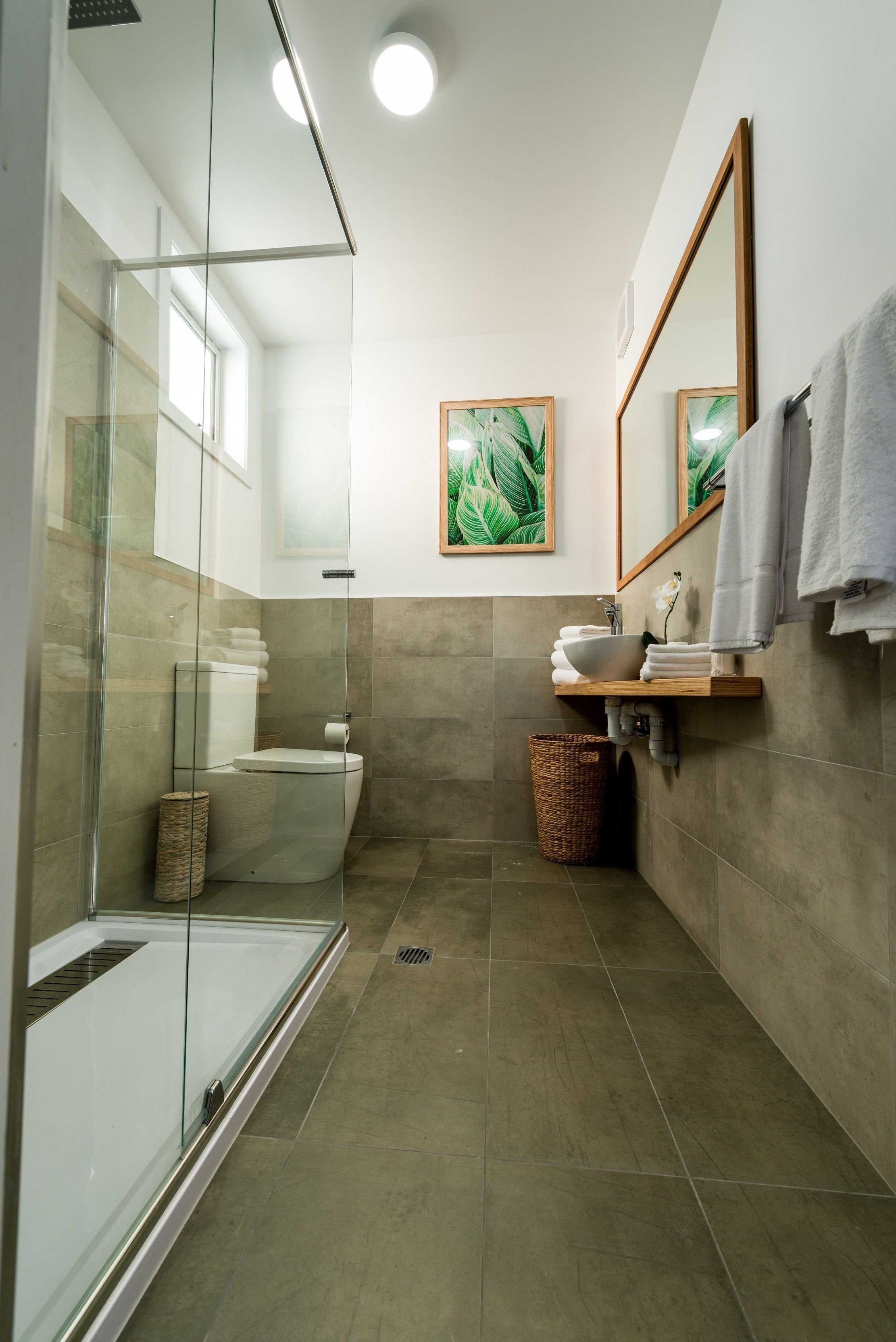 A modern bathroom with a glass shower enclosure, a toilet, a sink with a mirror, and a towel rack.