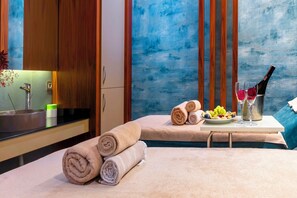 A hotel room with a bed, a small table with towels, a fruit plate, a bottle of wine, and a vase with flowers. - Starton Hotel & SPA (Ankara)
