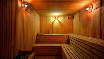A sauna with wooden benches and walls, and two wall-mounted light fixtures.