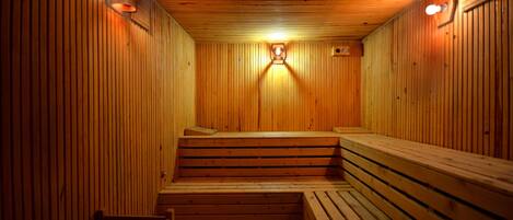 Una sauna con bancos y paredes de madera, y dos luces fijadas a la pared.