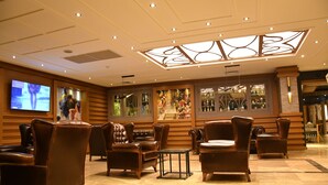 Un hall d’entrée avec des fauteuils en cuir, un téléviseur et un plafond décoratif.