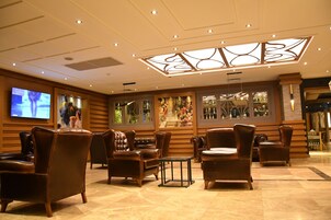 Um hall com poltronas de couro, uma televisão e teto decorativo.