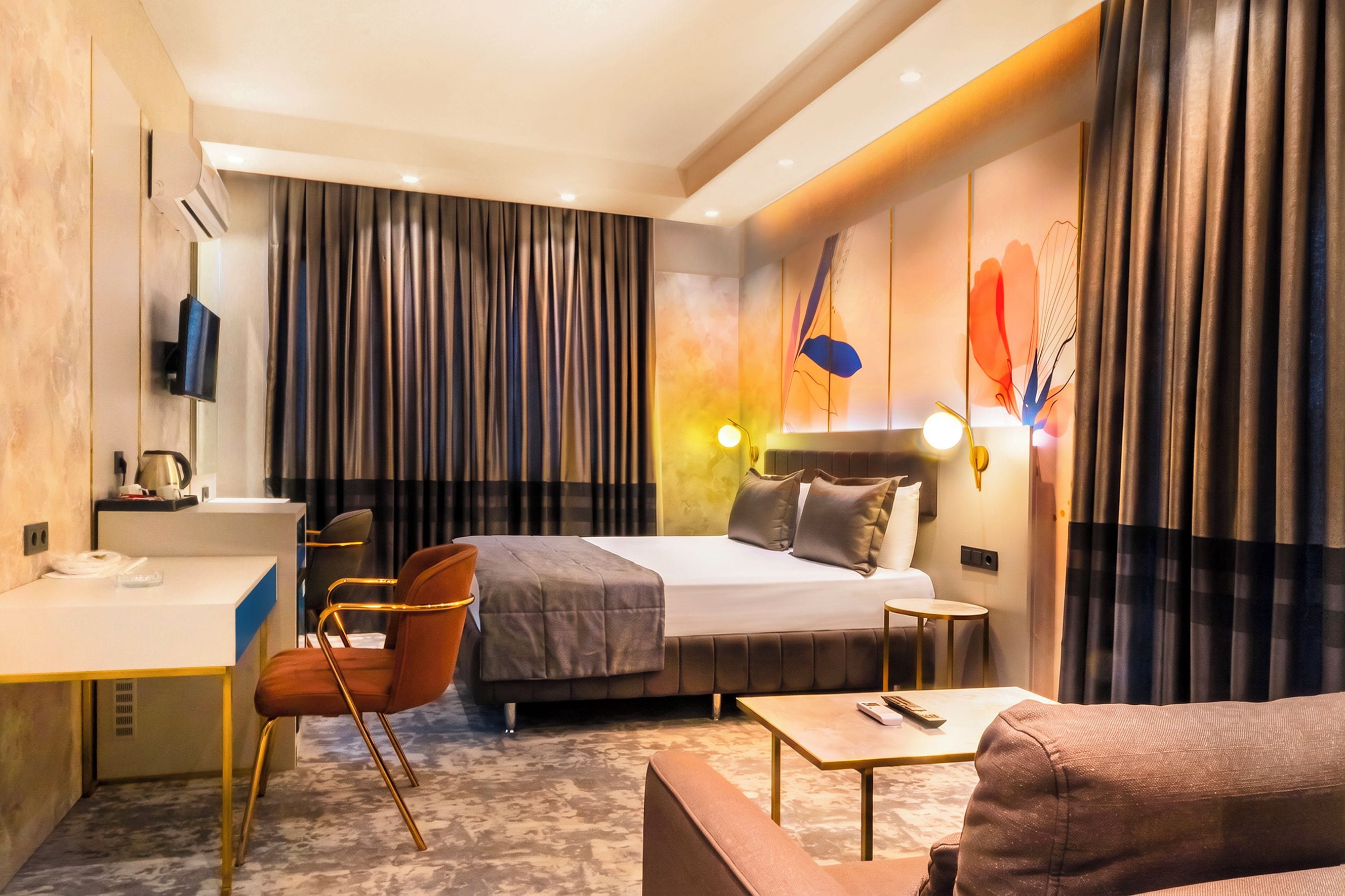 Una habitación de hotel con una cama, un escritorio, una silla, un sofá y una mesita.