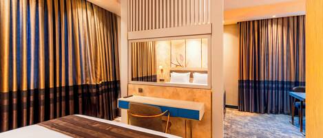 Habitación de hotel con cama, escritorio, silla y un espejo grande.