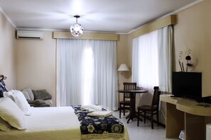 Ein Hotelzimmer mit einem Bett, einem Schreibtisch mit Fernseher, einem Sessel und einer Lampe.