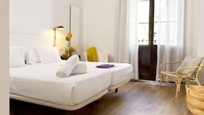 Una habitación de hotel con una cama, una silla, una lámpara y un ventanal.