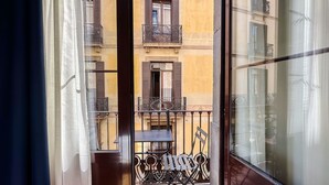 Vista desde un balcón con una mesa y sillas, que da a un edificio con balcones y ventanas.