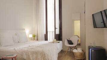 Una habitación de hotel con una cama, una silla, un televisor y una mesita.