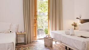 A hotel room with two beds, a small table, a chair, and a view of the outside. - Som Nit Triomf (Barcelona)