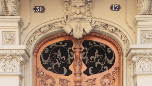 A large, ornate wooden door with intricate carvings, flanked by decorative columns and a detailed archway. - Som Nit Triomf (Barcelona)