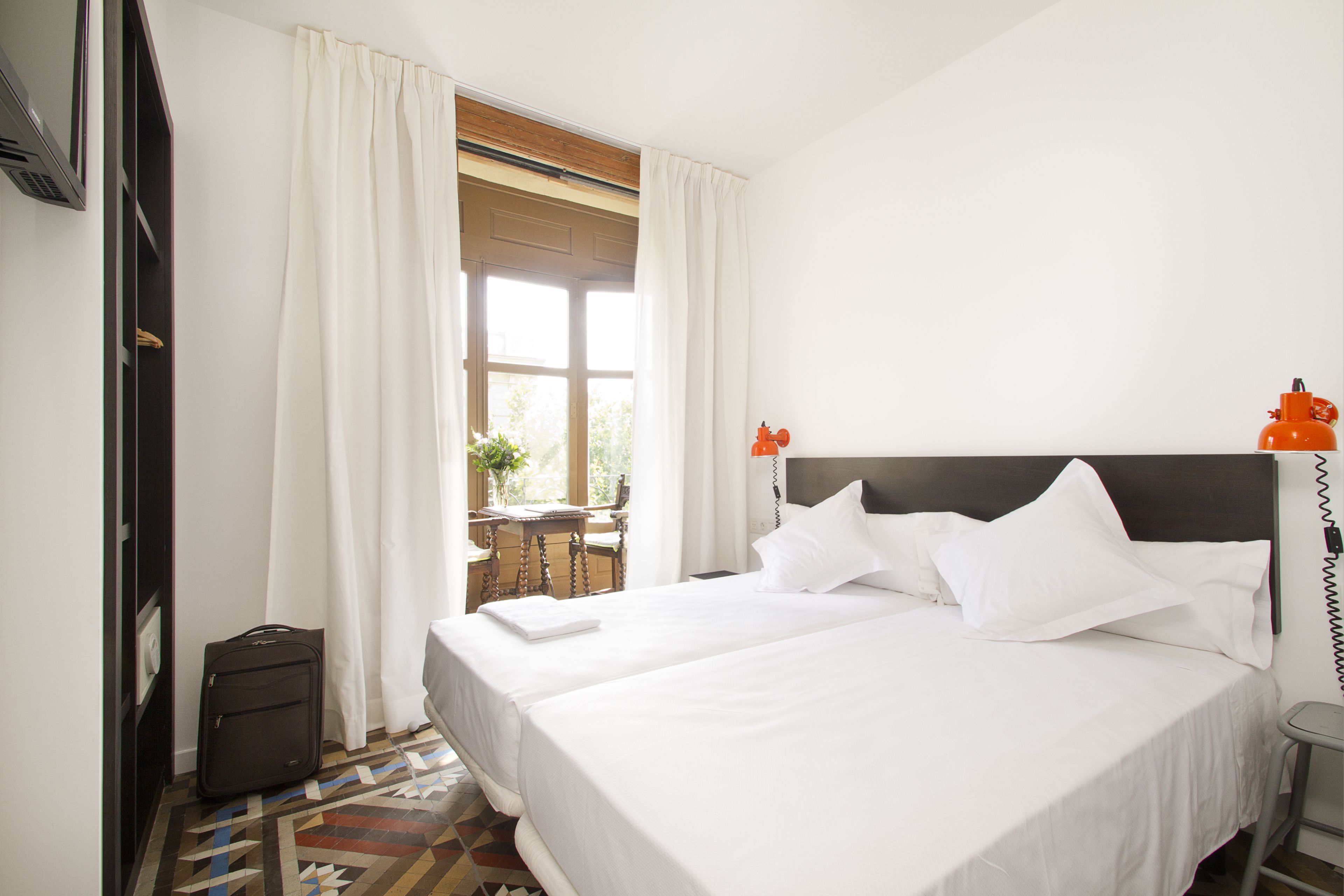A hotel room with a large bed, a desk, and a window with curtains.