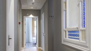 A hallway with patterned flooring, a door with a number, and a window with decorative glass. - Som Nit Triomf (Barcelona)