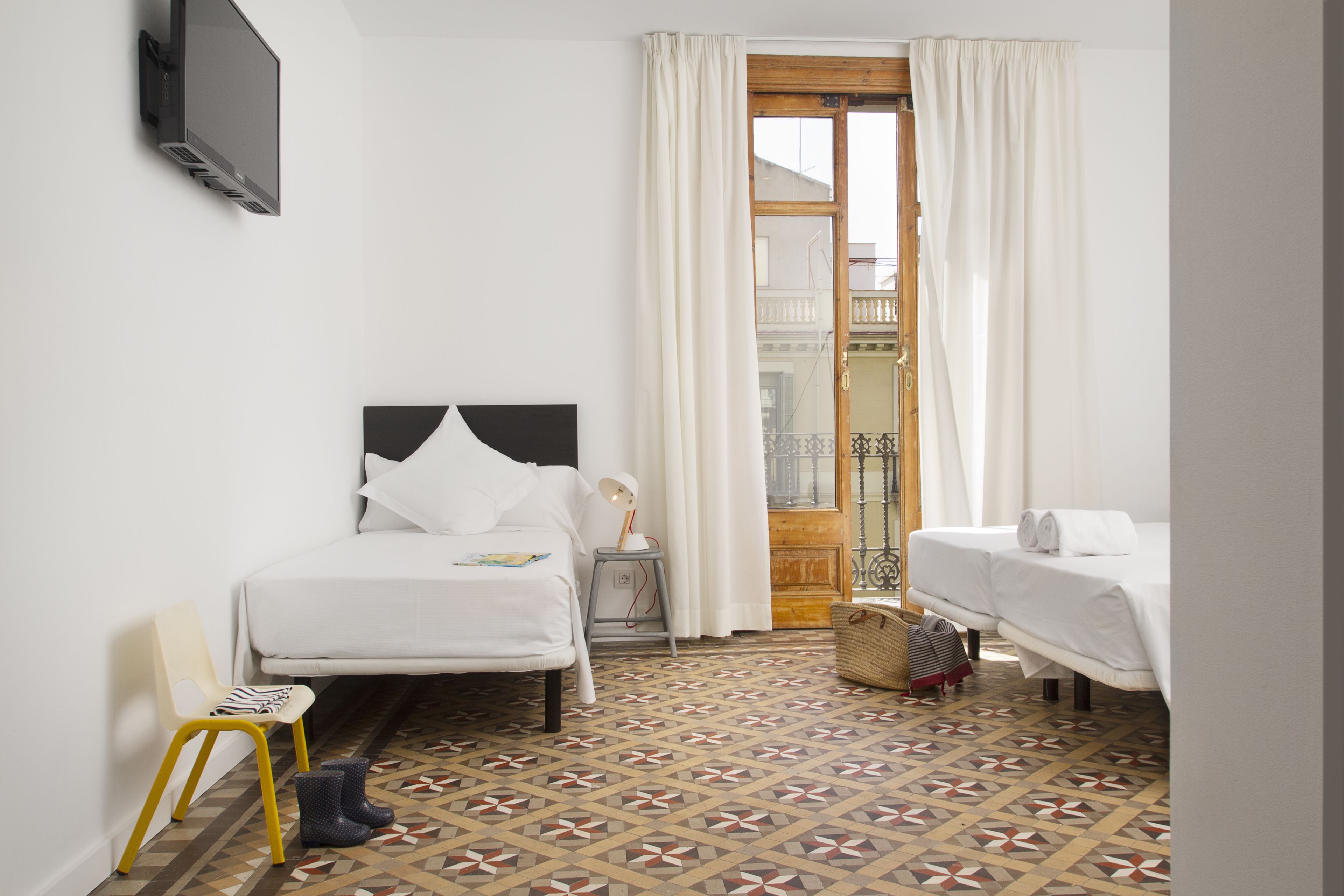 Een hotelkamer met twee bedden, een stoel, een televisie en een vloer met een patroon.