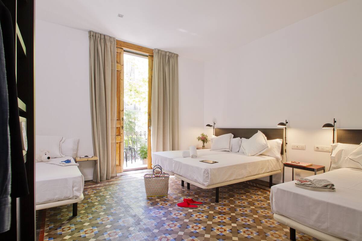 Habitación de hotel con dos camas, una mesita, una silla y piso estampado.