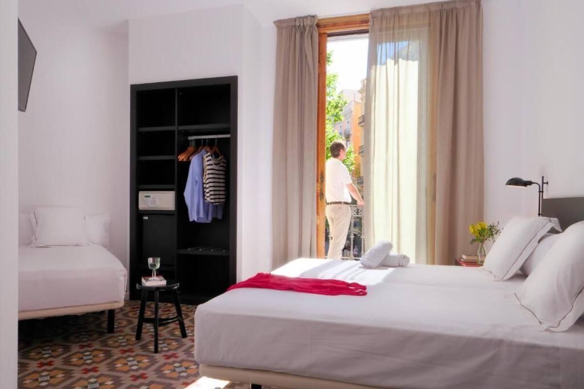 Habitación de hotel con cama, armario, una mesita con vaso y vistas al exterior.
