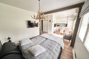 Une chambre avec un grand lit, un lustre et une vue sur la cuisine.
