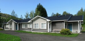 Une rangée de maisons de plain-pied, chacune dotée d’un garage, d’un porche abrité et d’un petit jardin.