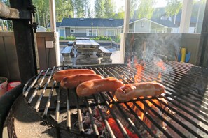 Un barbecue avec des saucisses en train de cuire à l’extérieur.