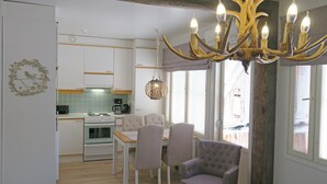 A modern kitchen with white cabinets, a dining table, and chairs. There is a chandelier with antler decorations. - Apartments Huili (Kuopio)