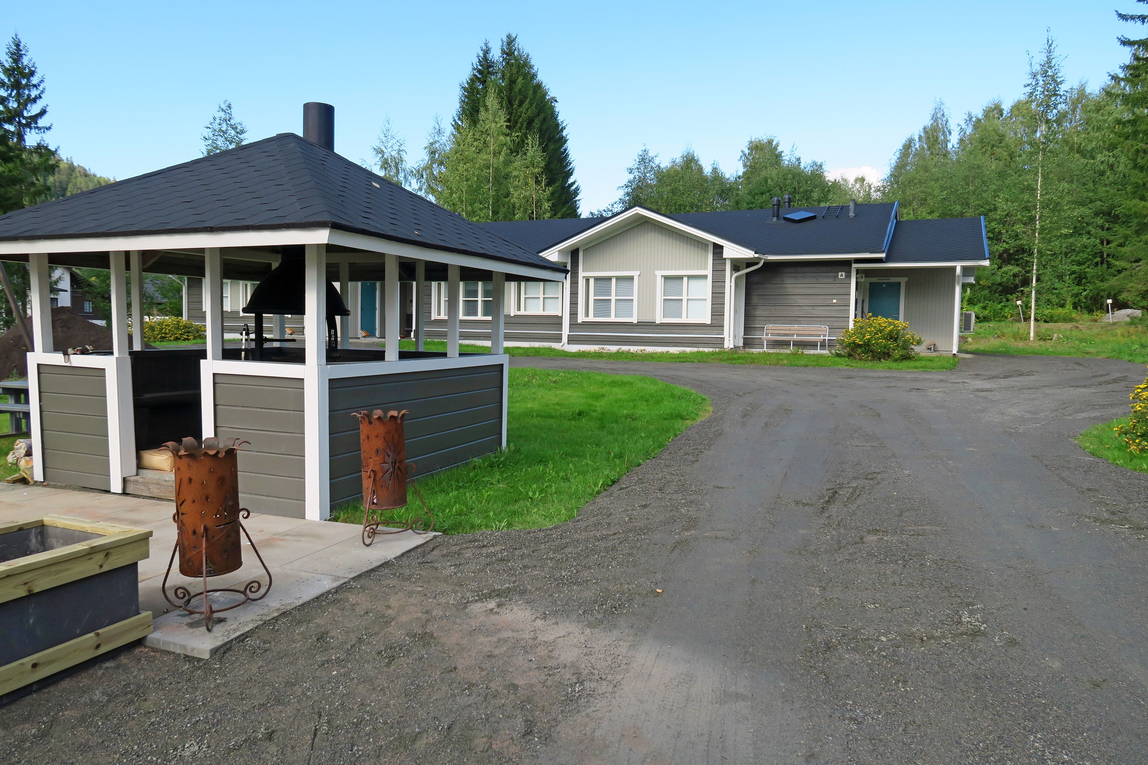 A row of cabins with a covered outdoor area and a dirt path leading to them.