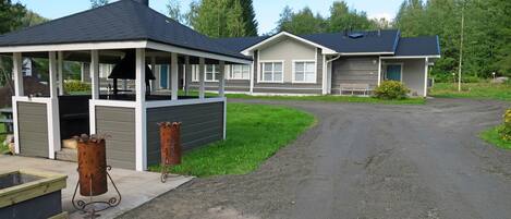 A row of cabins with a covered outdoor area and a dirt path leading to them.