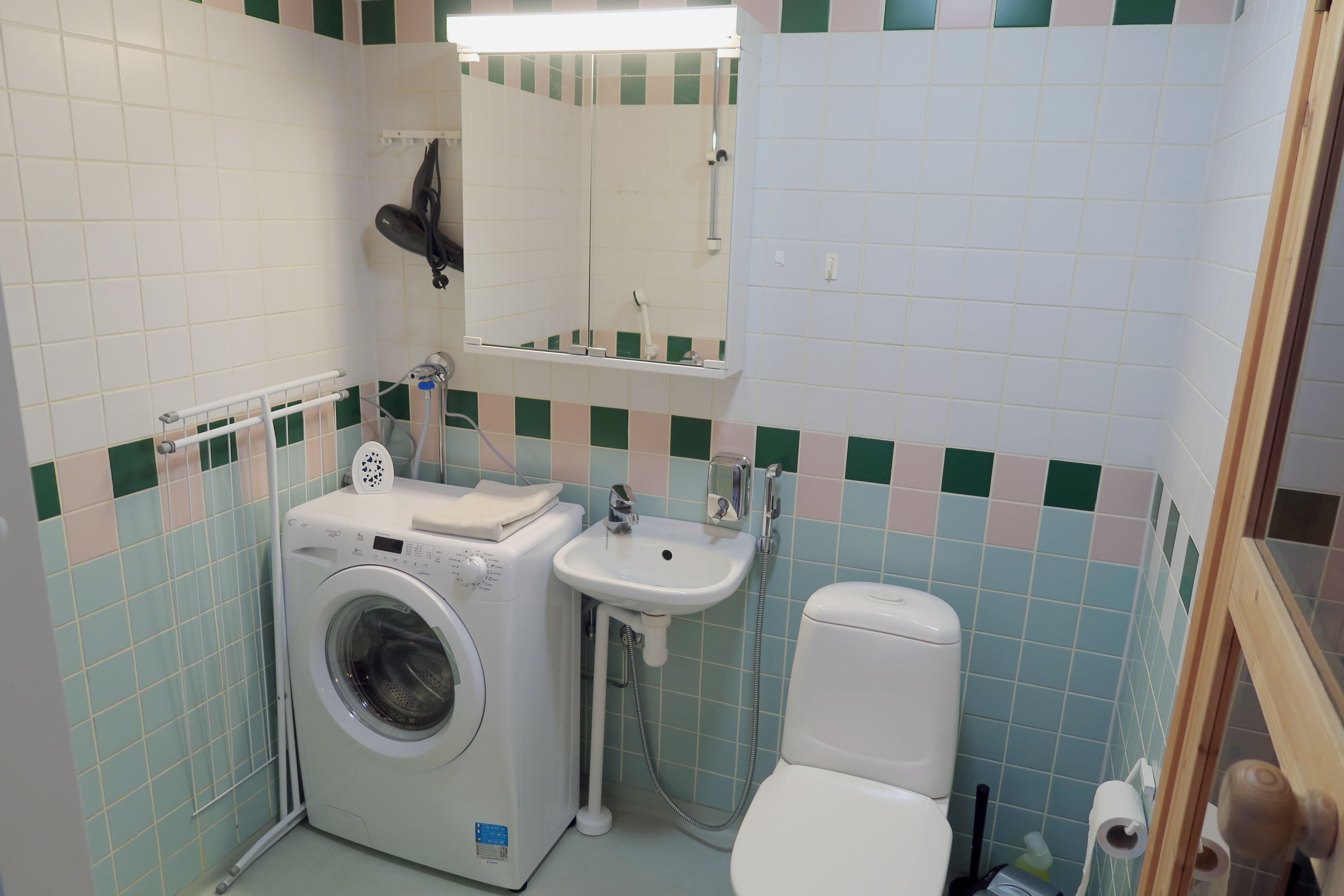 A compact bathroom with a washing machine, sink, and toilet.