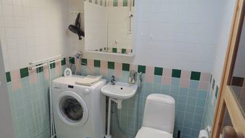 A compact bathroom with a washing machine, sink, and toilet.