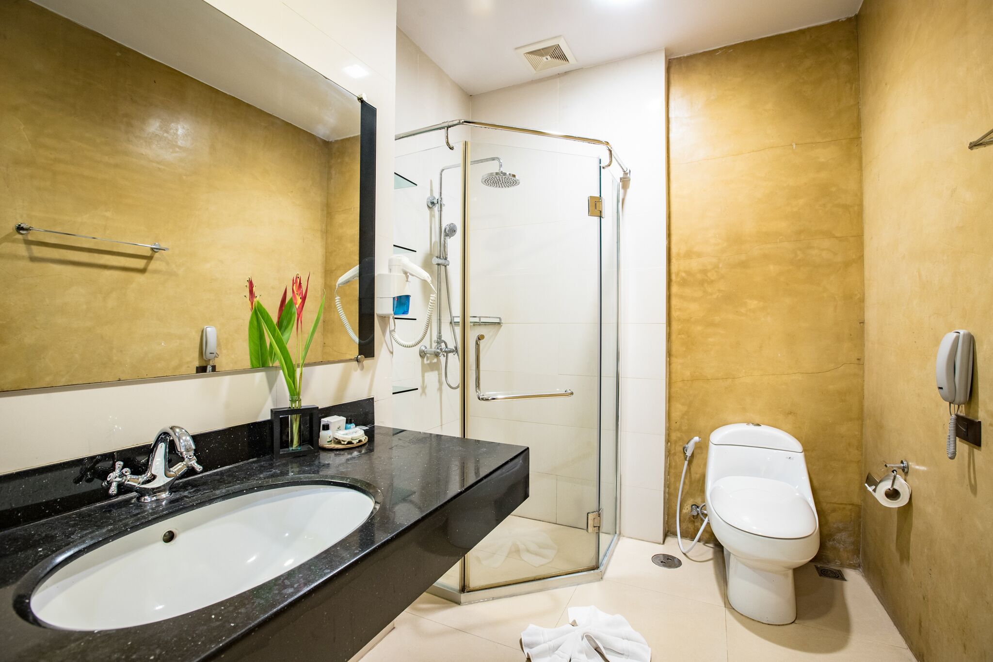 Un baño moderno con lavabo negro, cabina de ducha de cristal y inodoro blanco.