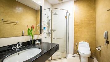 Un baño moderno con lavabo negro, cabina de ducha de cristal y inodoro blanco.