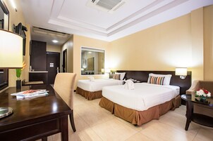 Habitación de hotel con dos camas, un escritorio, una silla, una mesa con flores y un espejo.