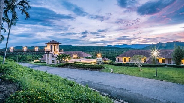 A resort with multiple buildings, a bridge, and a mountainous backdrop.