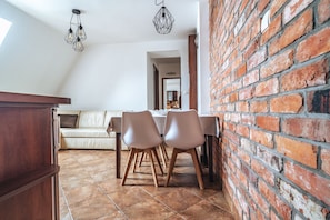 A dining area with a brick wall, a wooden table, and two chairs. - Willa Gardenia (Zakopane)