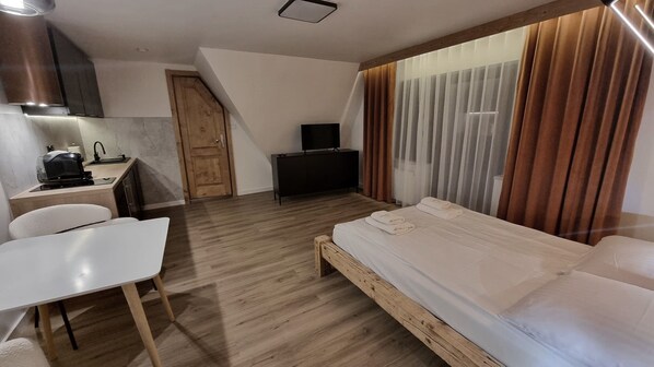 Una habitación de hotel pequeña con una cama, un escritorio, una silla, un televisor y un rincón americano.