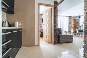 A modern kitchen with black cabinets, a wooden door, and a dining area with a table and chairs. - Willa Gardenia (Zakopane)