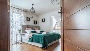 Un dormitorio con cama, mesita de noche y ventana con cortinas.