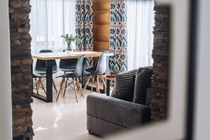 A dining area with a wooden table and chairs, a sofa, and a decorative plant. - Willa Gardenia (Zakopane)
