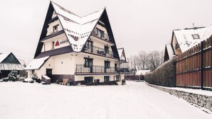 Un edificio de varios pisos con un techo triangular característico, un balcón y un cartel que dice 