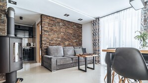 Una sala de estar moderna con un sofá gris, una mesa de centro de madera, una silla negra y una chimenea.
