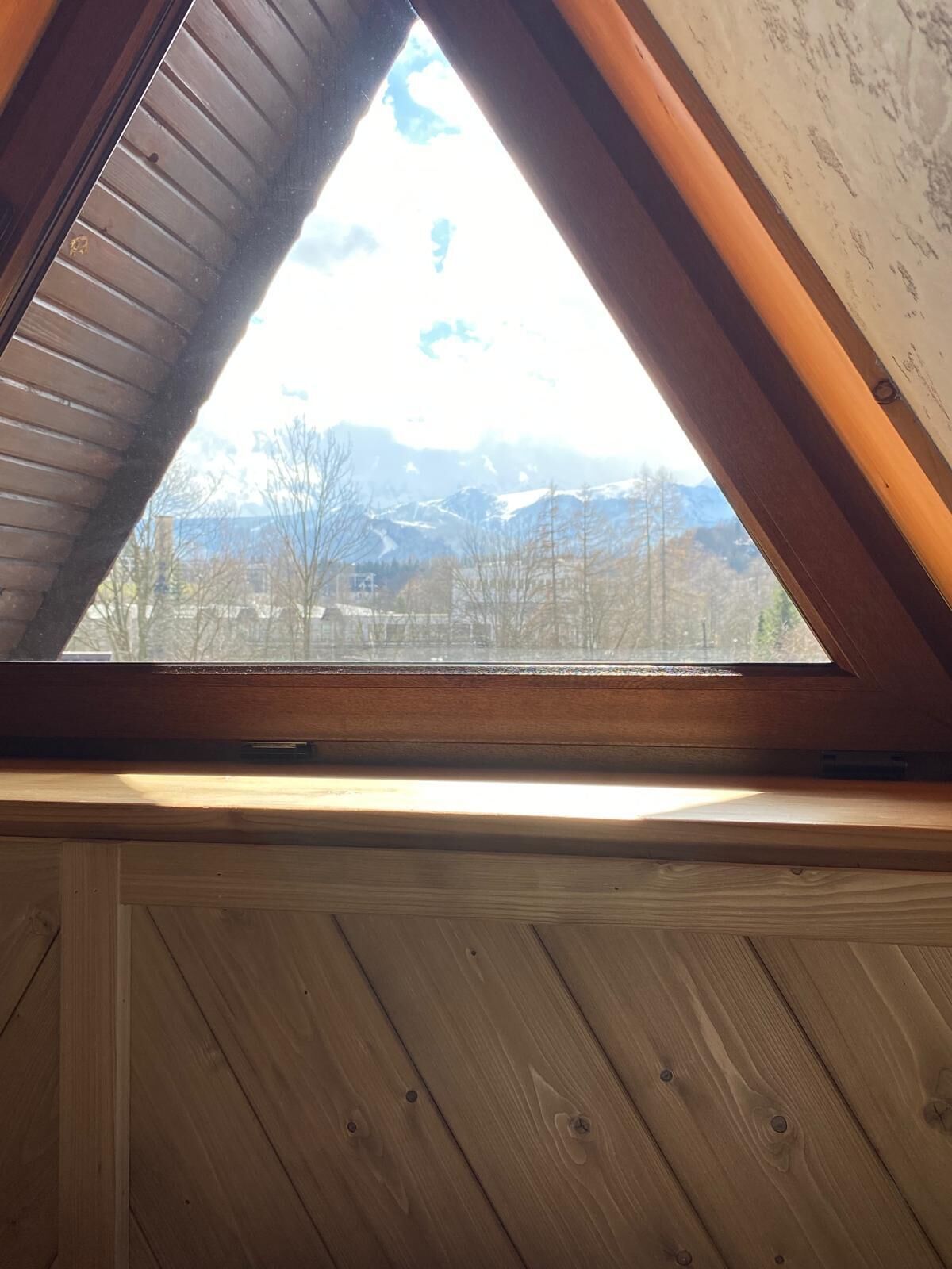 A triangular skylight with a view of a mountainous landscape.
