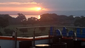 A sunset view from a balcony with outdoor seating and a railing. - Heron Hotel (Awassa)