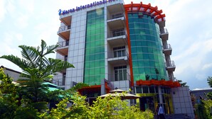 A modern hotel with a glass facade, multiple balconies, and a distinctive red and orange design element. - Heron Hotel (Awassa)