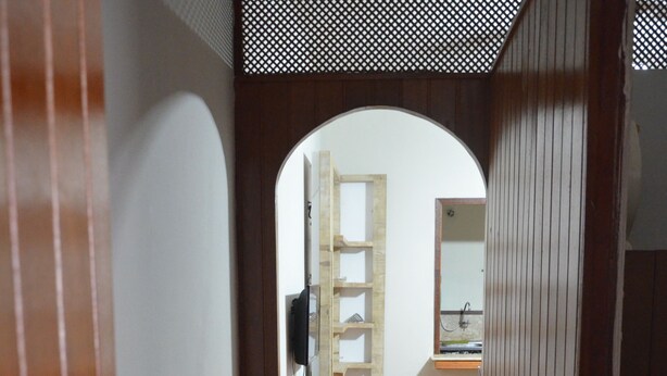 A hallway with wooden flooring, a wooden door frame, and a view into a room with a desk, shelves, and a mirror. - Copacabana Etrusco Apartment (Rio de Janeiro)