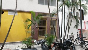 A yellow building with a metal gate and a motorcycle parked in front. - Copacabana Etrusco Apartment (Rio de Janeiro)